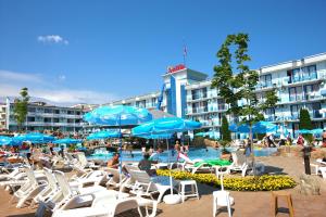 a pool with chairs and umbrellas in front of a hotel at Hotel Kotva - All Inclusive in Sunny Beach