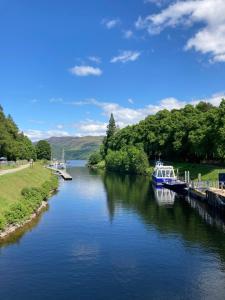 a boat is docked at a dock on a river at Loch Ness Pods in Fort Augustus
