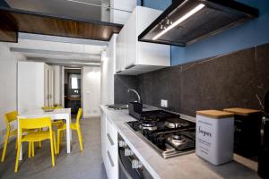 a kitchen with a stove and yellow chairs in it at Acquarò Suite Apartments in San Vito lo Capo