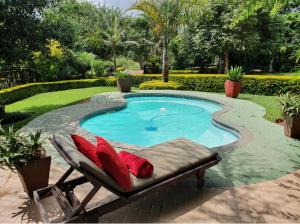 a pool with red pillows and a chair next to it at Palmwag Tzaneen in Tzaneen