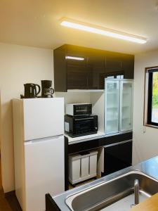 a kitchen with a white refrigerator and a microwave at 松田 Terrace A in Ginoza