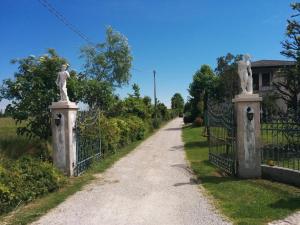 a gate with statues on it next to a dirt road at Agriturismo la Chioccia in Campagna Lupia