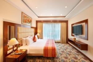 a hotel room with a bed and a flat screen tv at Accord Puducherry in Puducherry