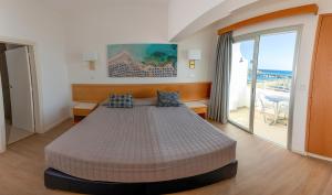 a bedroom with a bed with a view of the ocean at Tylos Beach Hotel in Kato Pyrgos