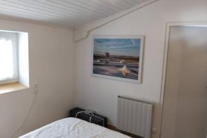 ブワンにあるLA MAISON BLEUEのベッドと壁に絵が飾られた寝室