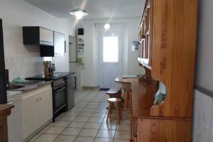 ブワンにあるLA MAISON BLEUEの白いキャビネットとテーブルと椅子のあるキッチン +2枚の写真