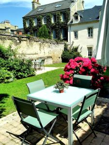 un tavolo bianco e sedie in un cortile fiorito di Apt cosy centre ville Bayeux avec terrasse ou extérieur proche plages du débarquement a Bayeux