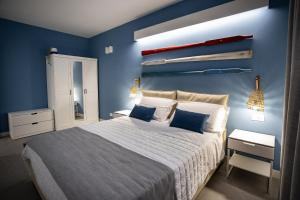 een slaapkamer met een groot bed met blauwe muren bij Acquarò Suite Apartments in San Vito lo Capo