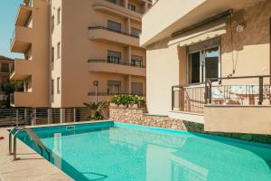 フィナーレ・リーグレにあるHotel Residence La Palmaのアパートメントの建物の前にスイミングプールがあります。