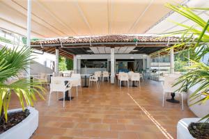 Studio-Apartments La Selva في غيفّا: مطعم بطاولات بيضاء وكراسي ونباتات