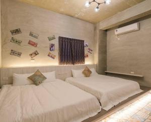 two beds in a bedroom with pictures on the wall at 澎湖海景民宿 島嶼時光 Island Time Homestay in Magong