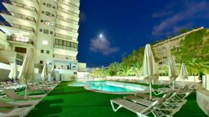 a resort with chairs and a pool and a building at Prince Park in Benidorm