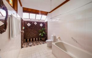 a bathroom with a tub and a toilet and a sink at Bali Taman Beach Resort & Spa Lovina in Lovina