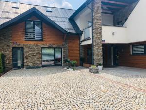 a brick house with a stone driveway in front of it at Apartament Huzar in Krynica Zdrój