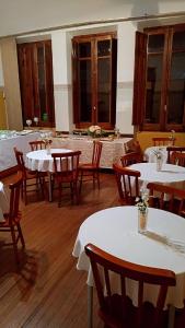uma sala de jantar com mesas brancas e cadeiras de madeira em Hotel Castelo em Santana do Livramento
