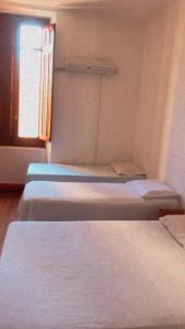 a row of beds in a room with a window at Hotel Castelo in Santana do Livramento
