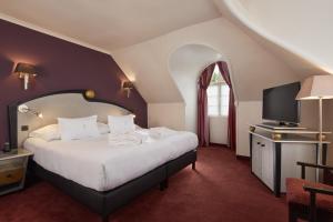 a bedroom with a large bed and a tv at Le Grand Hôtel Le Touquet-Paris-Plage in Le Touquet-Paris-Plage
