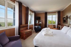 a hotel room with two beds and a chair and windows at Le Grand Hôtel Le Touquet-Paris-Plage in Le Touquet-Paris-Plage