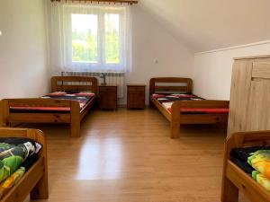 Habitación con 3 camas y ventana en Bieszczadzki dom nad stawem, en Ropienka