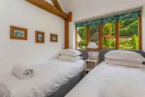 two beds in a room with a window at Carters Barn in Chipping Campden