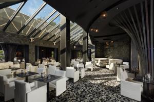 a restaurant with white chairs and tables and windows at Le Grand Hôtel Le Touquet-Paris-Plage in Le Touquet-Paris-Plage