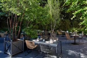 a patio with tables and chairs and trees at Le Grand Hôtel Le Touquet-Paris-Plage in Le Touquet-Paris-Plage