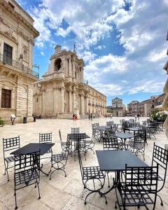a group of tables and chairs in front of a building at Ortigia Charme piazza Duomo in Siracusa