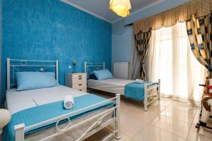 Duas camas num quarto com paredes azuis em Villa Angelina em Alykes