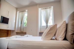 a bedroom with a large white bed with two windows at Chrysanthi's Apartment in Preveza