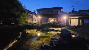 una casa con un estanque delante de ella por la noche en 1日1組限定 プライベート空間 古民家貸切コテージとけい en Kurita