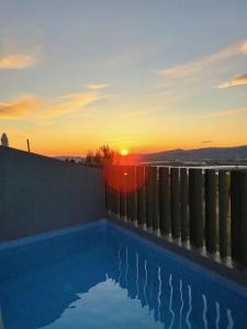 una piscina con il tramonto sullo sfondo di Casa Melocotón - Designhouse mit privatem Pool, direkt am Golfplatz a Caleta de Velez