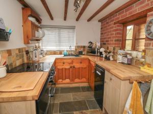 una cocina con armarios de madera y una pared de ladrillo en Ascot Cottage, en York