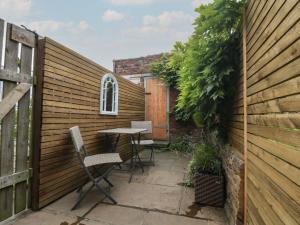 eine Terrasse mit zwei Stühlen und einem Tisch in einem Zaun in der Unterkunft Ascot Cottage in York