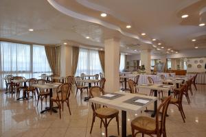 una sala da pranzo con tavoli, sedie e finestre di Hotel Gaston a Rimini