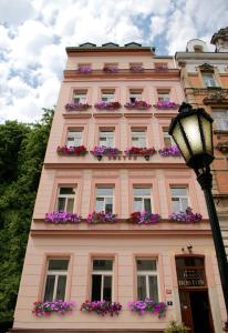 różowy budynek z skrzyniami kwiatowymi w obiekcie Hotel Boston w Karlowych Warach