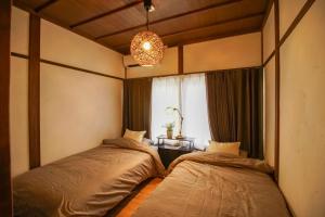two beds in a room with a window at 1日1組限定 プライベート空間 古民家貸切コテージとけい in Kurita
