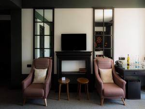 a living room with two chairs and a television at Esquisse Design Hotel in Tʼelavi