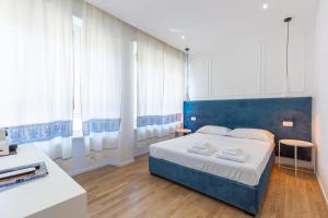 ein Schlafzimmer mit einem blauen Bett in einem Zimmer mit Fenstern in der Unterkunft ALMi in Cagliari