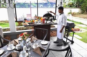 un uomo in piedi davanti a un tavolo che prepara il cibo di Cocoon Hills a Nuwara Eliya