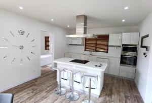 a white kitchen with a large clock on the wall at Villa Aussee Mauritius in Trou aux Biches