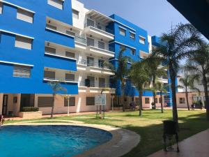 an apartment building with a swimming pool and palm trees at Cala Iris Appartement de vacances in Martil