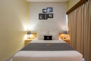 a bedroom with a large white bed with a brick wall at Paisa Seminyak Living in Seminyak