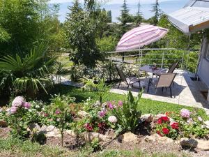 een tuin met een tafel en een parasol en bloemen bij View Topia Apartments in Ohrid