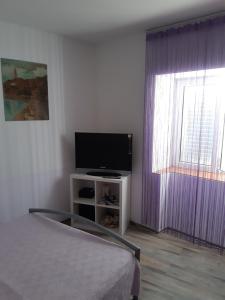 - une chambre avec une télévision et des rideaux violets dans l'établissement Elena Mare, à Novi Vinodolski