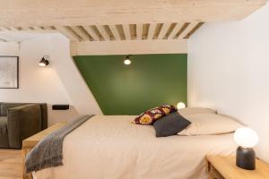 een slaapkamer met een bed met een groene muur bij Les Cocon des Pentes de la Soie in Lyon