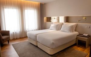 a bedroom with a large white bed and a chair at Hotel Cristal Setúbal in Setúbal