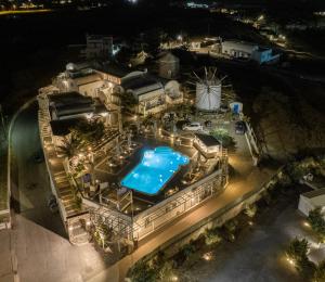 una vista panoramica su una piscina di notte di Milos Villas Hotel a Firà