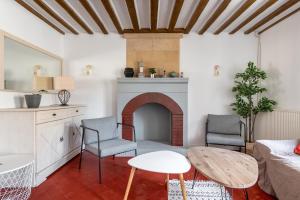 a living room with a fireplace and two chairs and a table at L'escalier rouge - Maison rénovée avec cour in Luc-sur-Mer