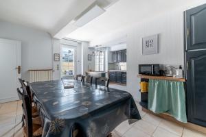 a dining room with a table and a kitchen at L'escalier rouge - Maison rénovée avec cour in Luc-sur-Mer