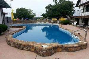 a swimming pool with a stone wall around it at OYO Hotel Windmill Branson in Branson